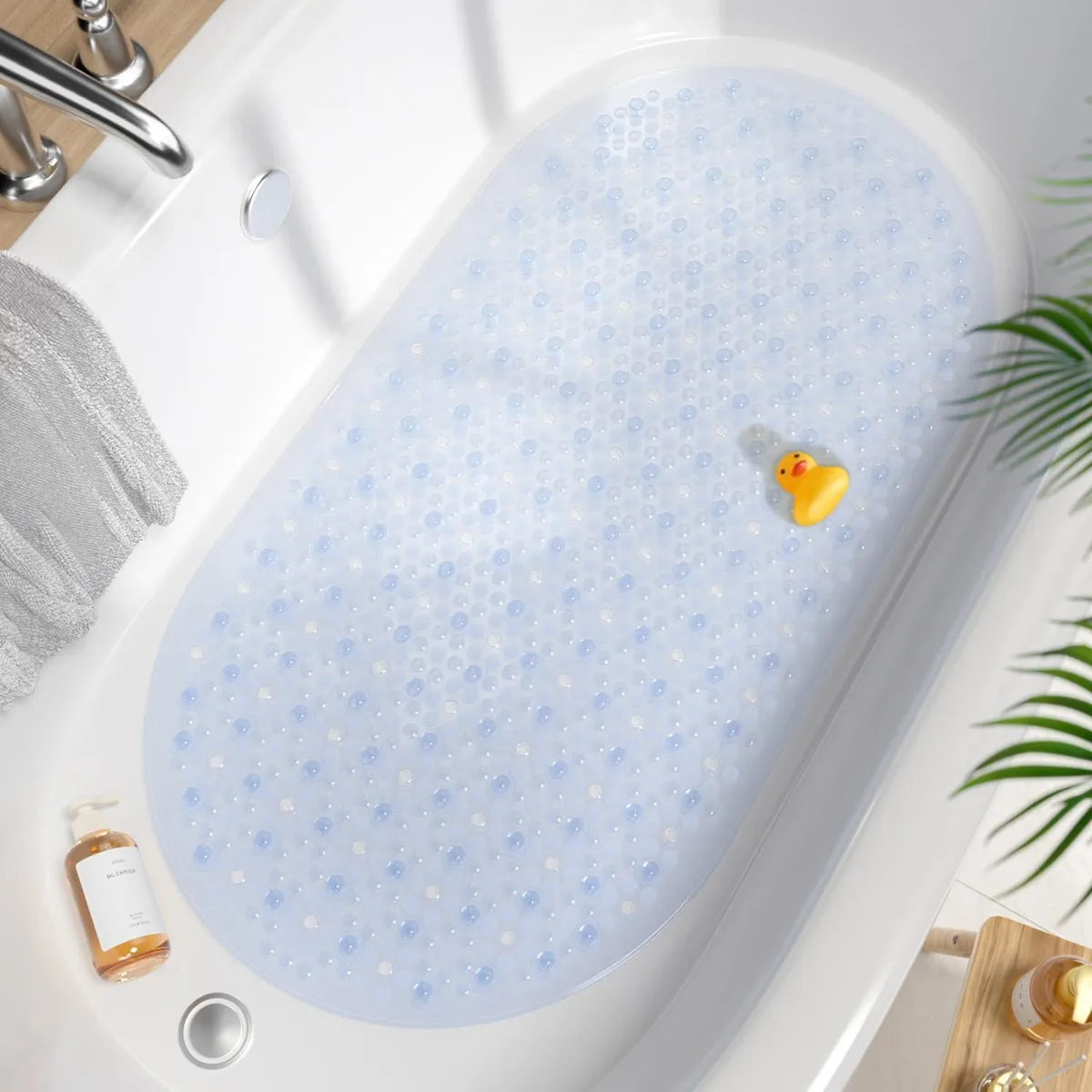 Clear oval bath mat with bubble texture and suction cups, 27 by 15 inches