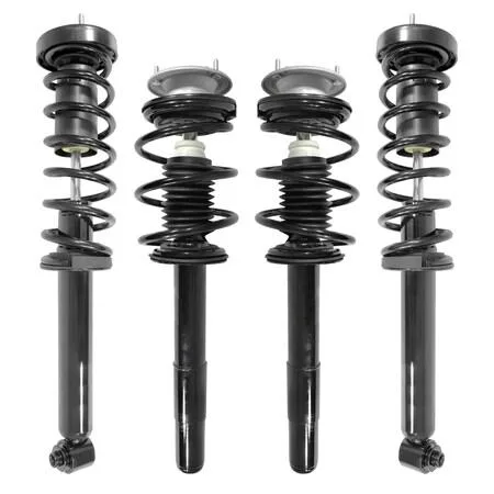 Four silver strut assemblies with black coil springs on grey background