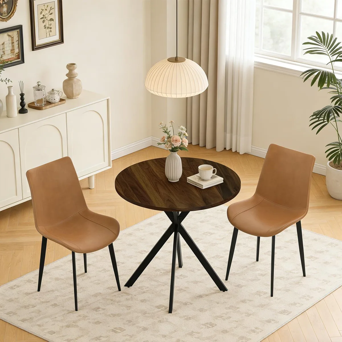 Round walnut table with X-shaped legs and two beige upholstered chairs