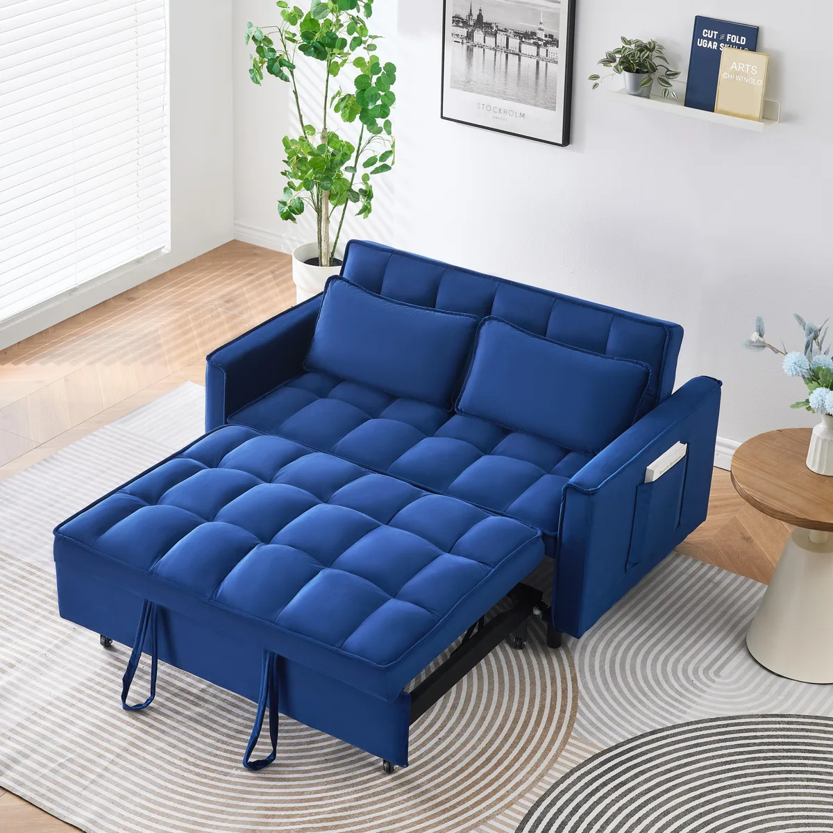 Blue velvet sofa bed with curved backrest and side pockets