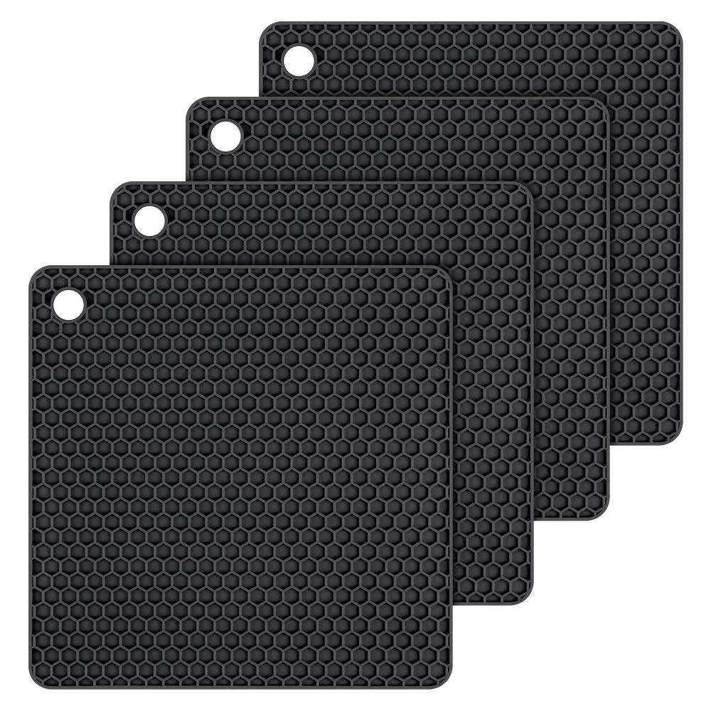 Four black honeycomb silicone trivet mats with hanging holes
